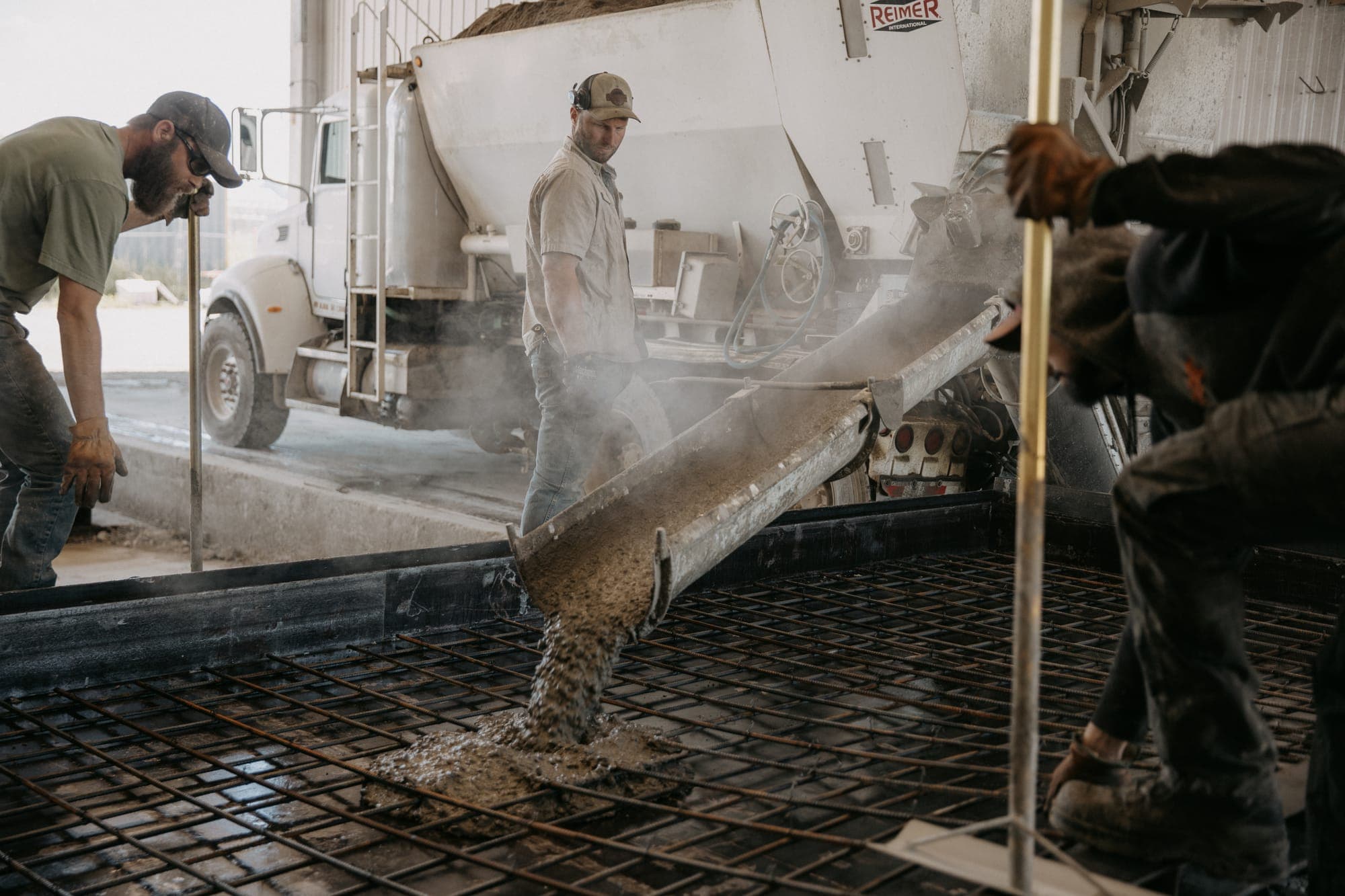 AltaMix crew pouring concrete from the mixer chute over a rebar grid — the real precast business behind the site PolarVisuals built.