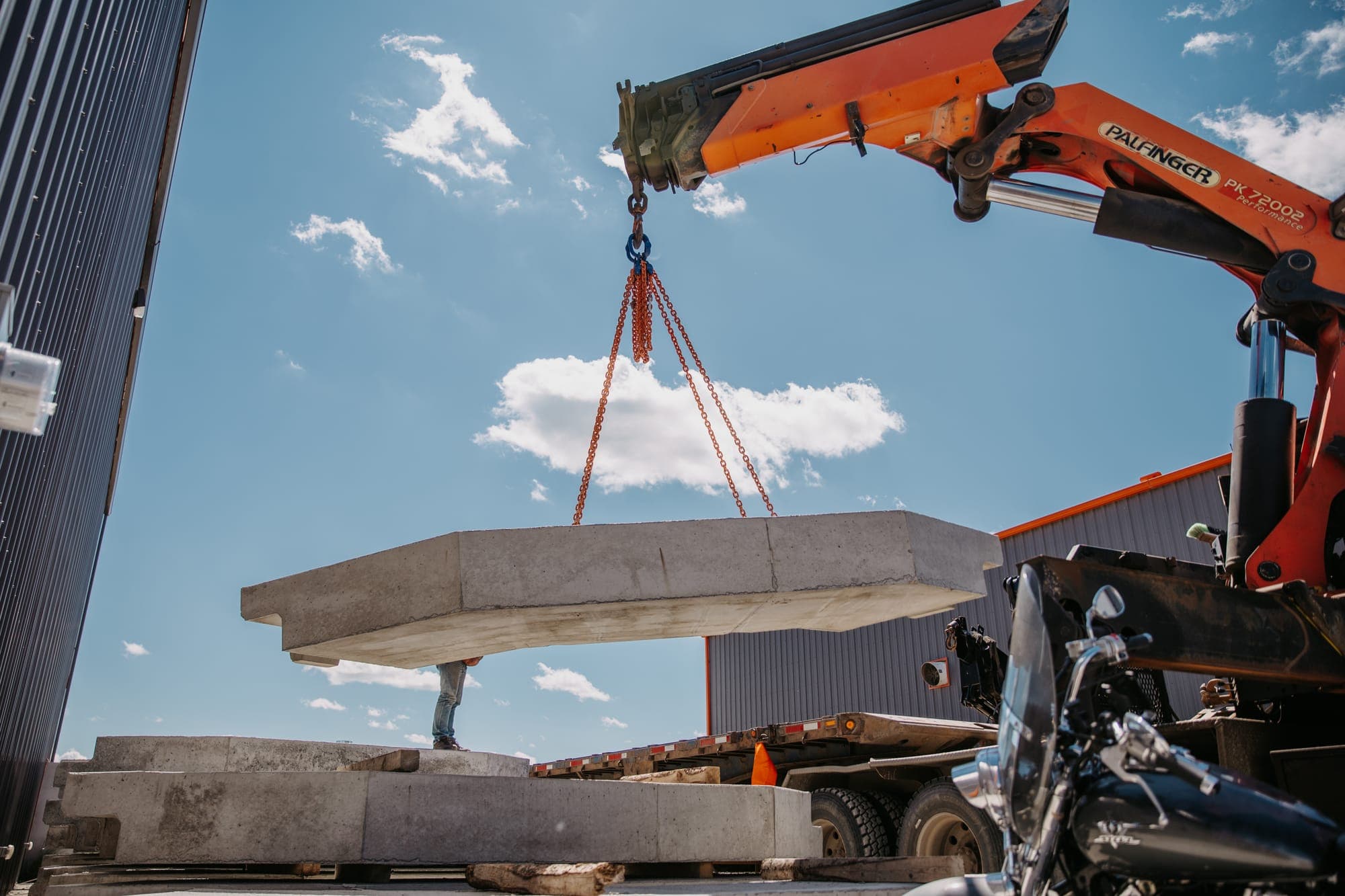 A truck crane hoisting a precast pad against a blue sky — the kind of on-site delivery work the ONSITE build is built to win.